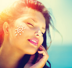 Beauty Girl Applying Sun Tan Cream on her Face. Sun Tanning