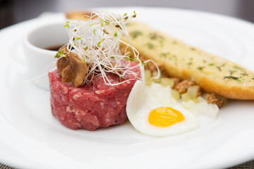 Close up of tartare beef with fried egg and garlic bread