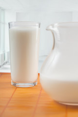 The jug and glass with milk stand on a table