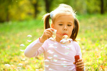 Little girl is blowing a soap bubbles