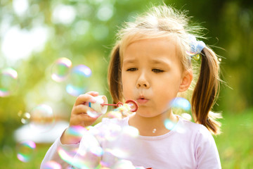 Little girl is blowing a soap bubbles