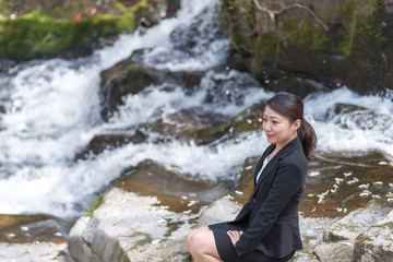 自然の中でリラックスするアジアのスーツの女性