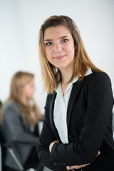Cheerful young business woman standing up in the office
