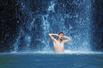 Handsome young man refreshing in waterfall in bali