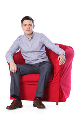 a young man in a red armchair isolated on white background