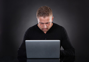 Man or hacker working on a laptop at night