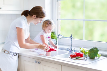 Young beautiful mother and her toddler daughter in kitchen