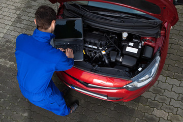 Mechanic Using Laptop While Repairing Car