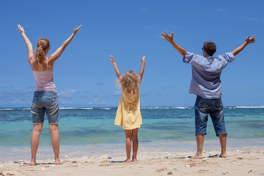 Happy family standing on the beach in the day time