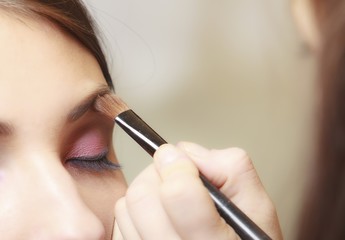 Makeup artist applying with brush cosmetic on eyebrow of woman