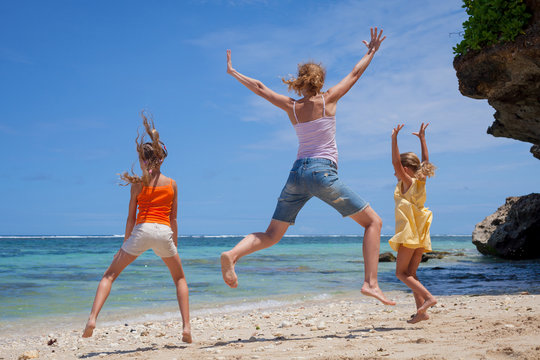 Happy family jumping at the beach in the day time