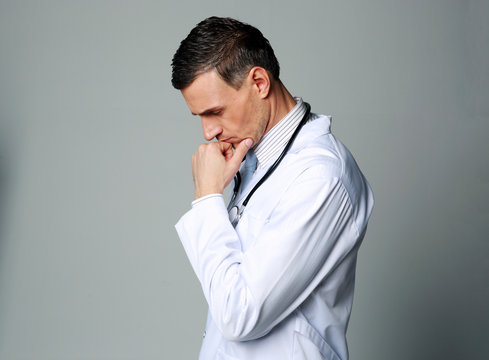 Portrait Of A Thoughtful Male Doctor On Gray Background