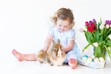 Fototapeta na wymiar Cute toddler girl with a bunny on Easter next basket with eggs