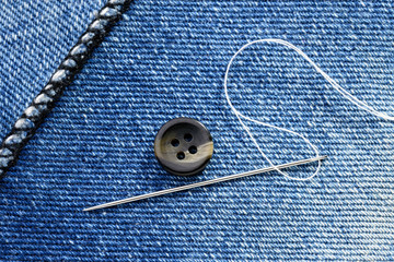 Sewing a button on  blue jeans fabric