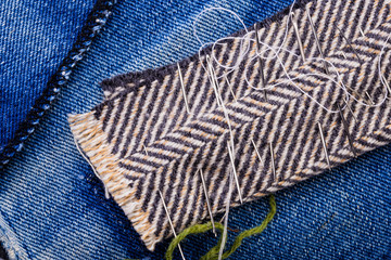 Fototapeta na wymiar Various needles ready to needlework with blue jeans and fabric