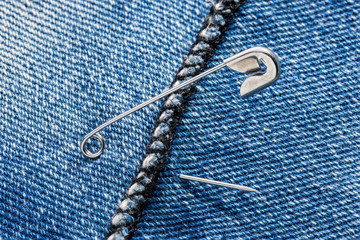 Open safety pins on a blue jeans denim fabric