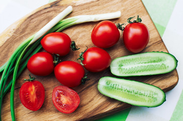 red tomatoes and green onions on cutting board