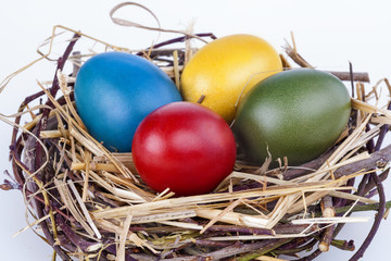 Colourful Easter eggs in a nest on white background
