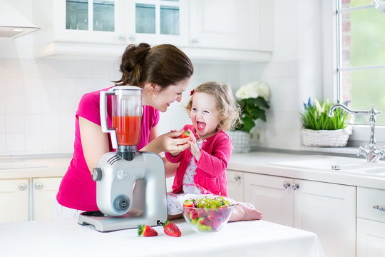 Funny toddler girl and her young mother makin breakfast