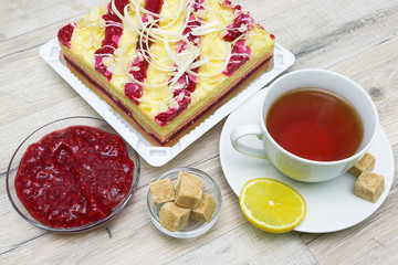 cup with tea, jam and cake on wooden table