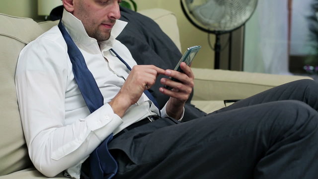 businessman sitting on the sofa and using his cellphone