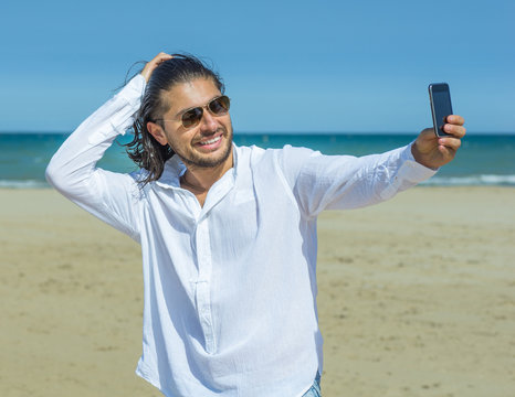 man takes a self portrait on the beach
