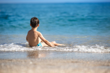Fototapeta na wymiar Little boy splashing in ocean waves