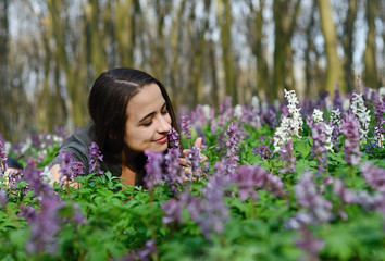 Beautiful young girl on a sunny day in spring forest among flowe