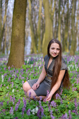 Beautiful young girl on a sunny day in spring forest among flowe
