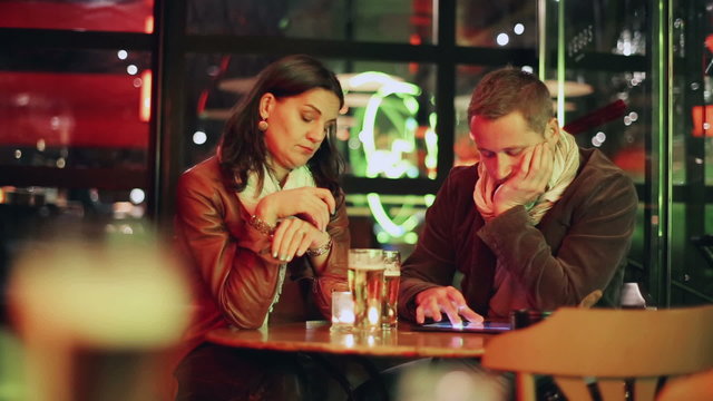 Bored couple sitting in pub at night, steadycam shot