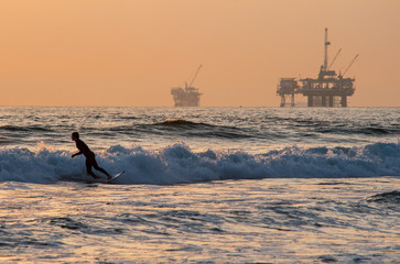surfing on huntington beach with oil rigs in background