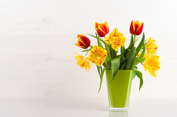 Tulips in a vase on a white wooden background