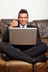 Handsome happy businessman at the computer shows finger up