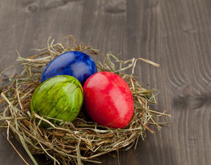 Easter eggs in hay nest on dark wood