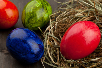 Easter eggs in hay nest on dark wood