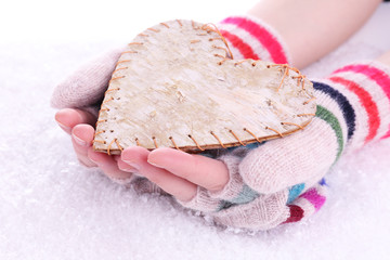 Female hands in mittens with heart on snow background