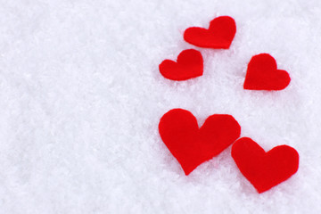 Little felt hearts on snowy background
