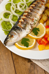 Delicious grilled fish on plate on table close-up