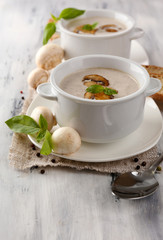 Mushroom soup in white pots, on napkin, on wooden background