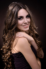 Naklejka premium Beautiful young woman with long hair on dark brown background