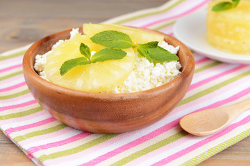 Bowl of tasty cottage cheese with pineapple on wooden table