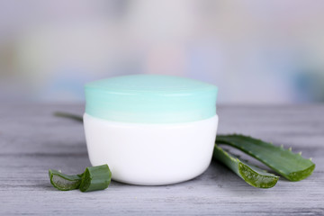 Cream and fresh green aloe leaves on wooden table