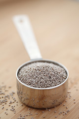 White chia seeds in a measuring cup on a cutting board