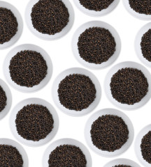 many black pepper in white dish on white background