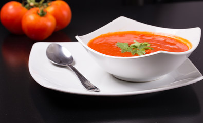 tomato soup with fresh tomatoes on black background