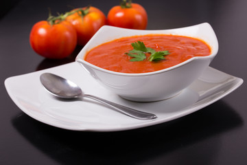 tomato soup with fresh tomatoes on black background