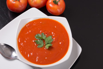 tomato soup with fresh tomatoes on black background