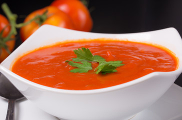 tomato soup with fresh tomatoes on black background