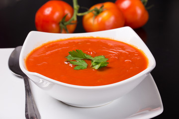 tomato soup with fresh tomatoes on black background