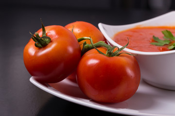 tomato soup with fresh tomatoes on black background